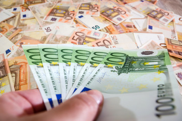 100 euro banknote in hands on a euro background. A lot of money for the background. Business concept.