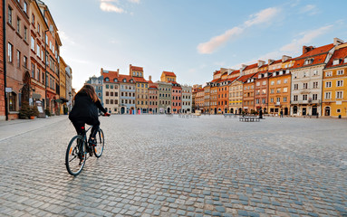 Woman on a bike rides on an empty Old Town Square in Warsaw, Poland - obrazy, fototapety, plakaty