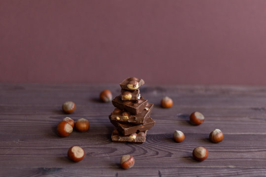 Pieces of dark chocolate with nazel nuts on brown wooden backgrouns