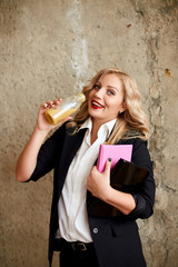 A girl in a suit drinks juice from a bottle and smile. Food delivery