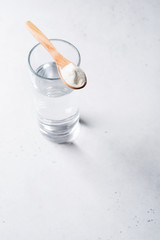 Collagen powder in spoon on glass of water, supplement, healthy and anti age concept flat lay on white background