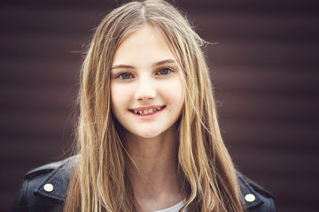 Fototapeta premium close-up portrait of little beautiful stylish kid girl with long flowing hair against a brown striped wall