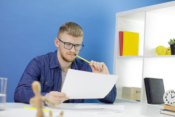 Young handsome animator designer in creative process, working on creating heroes, draws pencil...
