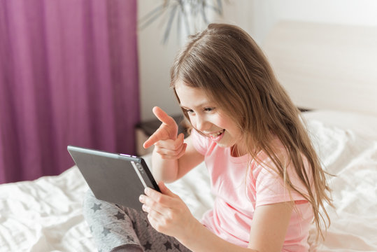 Happy girl chatting online at home on the bed