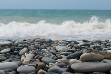 A small storm three or four points at sea, the wave hits the shore with a large pebble.