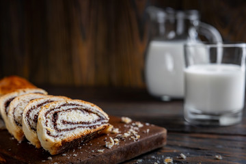Baking, pie with poppy seeds cut into pieces, on a wooden table in a rustic style, selective focus, shallow depth of field, low light, in the background a glass of milk