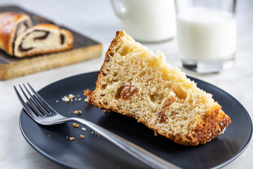 Pie with poppy seeds sliced into pieces, on wooden boards and in a dish, a glass and a jug with milk, selective focus, shallow depth of field, light background, top lighting.