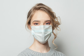 Young woman in a face mask on white background. Woman in medical mack. Flu epidemic and virus...