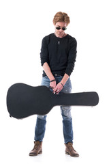 Handsome young red hair rocker man holding acoustic guitar black leather case looking down. Full...