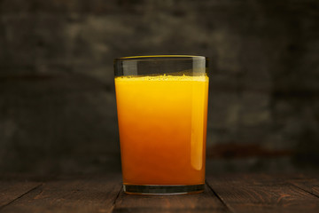 Fresh orange juice on a wooden table - natural and healthy food and drink. One glass of cocktail