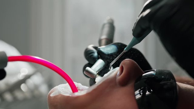 Patient in black safety glasses during tooth treatment. Stomatologist use dental instruments at treating teeth in dentist's office. Close-up.