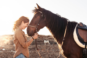 Young farmer cuddling her horse inside stable - Happy girl playing with animals in corral ranch - Human and animals relationship concept