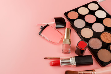 Various makeup productson pink background with copyspace