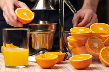 Squeezing an orange with a manual press, close view, making a glass of fresh. Fresh oranges on a...