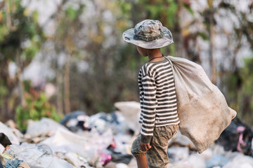 Obraz premium A poor boy collecting garbage waste from a landfill site. Concept of livelihood of poor children.Child labor. Child labor, human trafficking, Poverty concept