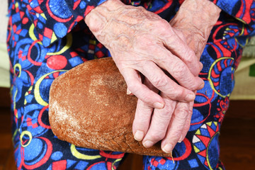 View from above. In her hands an old grandmother of 90 years holds bread, poverty and misery, the...