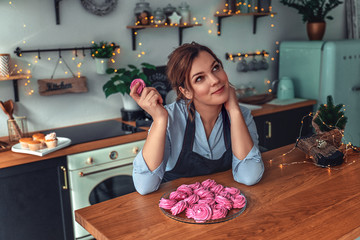 Portrait of a home confectioner in the kitchen. Woman cook cooks in the kitchen. Confectioner tastes marshmallows and prepares sweets.