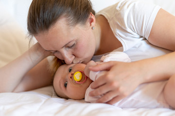 Obraz na płótnie Canvas Loving mother kisses her baby girl