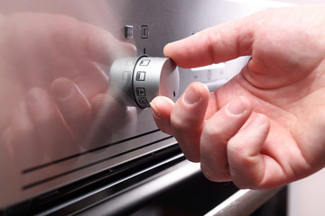 Hand holding rotate dial circle button heat of microwave oven for cooking food in kitchen room at home, Closeup.Close up of oven adjustment knob.
