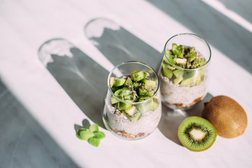 Healthy breakfast. chia pudding with kiwi and granola in glass on white background