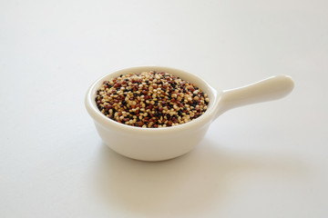 Quinoa seeds in the white cup isolated on white background.  Quinoa is a good source of protein for people following a plant-based diet. 