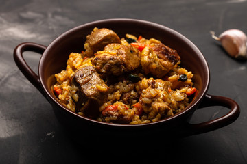 Large portion of pilaf in a clay dish. Delicious uzbek homemade meal