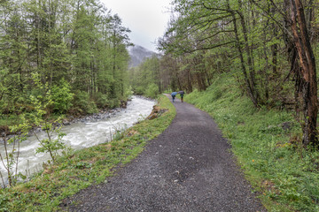 Couple out walking by the river in the rain in the pretty French Alpine village of Les Contamines