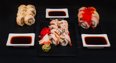 Japanese cuisine. Set of sushi with ginger on black stone plate on black background. Top view
