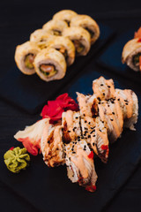 Japanese cuisine. Japanese sushi with soy sauce and wasabi on black stone plate on black background.
