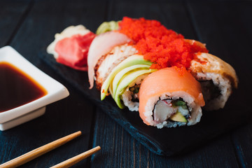 Japanese cuisine. Japanese sushi with soy sauce and wasabi on black stone plate on black background.