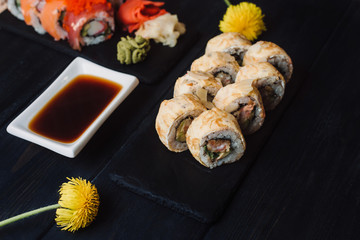 Japanese cuisine. Japanese sushi with soy sauce and wasabi on black stone plate on black background.
