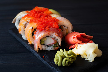 Japanese cuisine. Japanese sushi with soy sauce and wasabi on black stone plate on black background.
