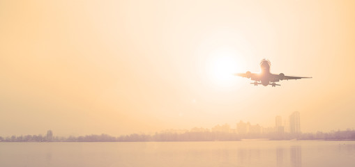 Airliner over the lake outside the city. Evening sunset