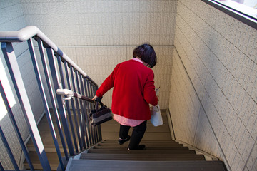 荷物を持って階段を降りている高齢女性