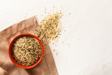 Cannabis kernels in a brown bowl on a white table