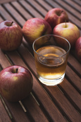 on a table freshly picked apples and a glass with fresh apple juice
