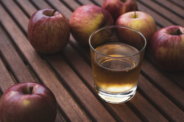 on a table freshly picked apples and a glass with fresh apple juice