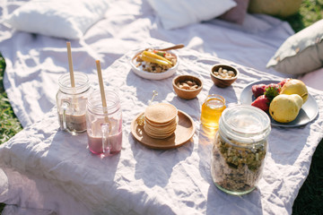Beautiful cozy summer or spring picnic with cocoa, pancakes, honey, strawberries, pears and granola.