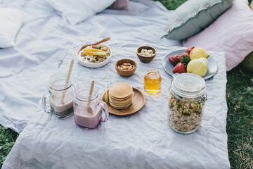 Beautiful cozy summer or spring picnic with cocoa, pancakes, honey, strawberries, pears and granola.