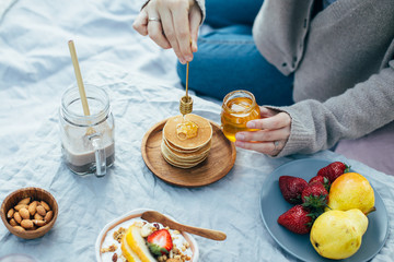 Beautiful cozy summer or spring picnic with cocoa, pancakes, honey, strawberries, pears and granola.