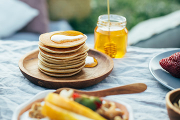 Beautiful cozy summer or spring picnic with cocoa, pancakes, honey, strawberries, pears and granola.