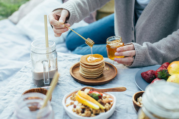 Beautiful cozy summer or spring picnic with cocoa, pancakes, honey, strawberries, pears and granola.