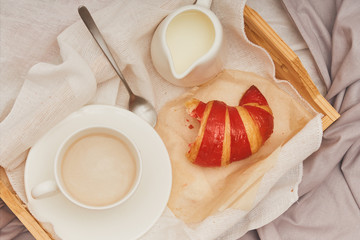 Breakfast in bed, coffee with cream, croissants in jam