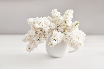 Bouquet of white lilac in vase on table in kitchen. Happy birthday greeting card. Hello spring and summer. Greeting card for Women's Day and Mother's Day. Spring season, copy space