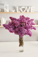 Large beautiful spring bouquet of lilac in vase on table in kitchen.Hello spring and summer. Greeting card for Women's Day and Mother's Day. Spring season, copy space.Good morning concept.Cozy morning