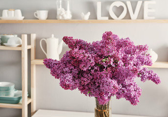 Large beautiful spring bouquet of lilac in vase on table in kitchen.Hello spring and summer. Greeting card for Women's Day and Mother's Day. Spring season, copy space.Good morning concept.Cozy morning