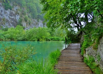 Fototapeta na wymiar Sendero de madera flotante que discurre a orillas de uno de los lagos de aguas turquesa en el Parque Nacional de Plitvice