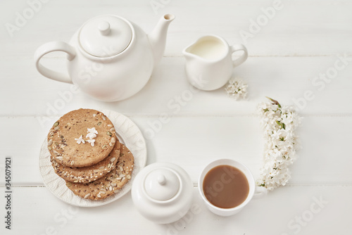 Tea set, cookies and white lilac on kitchen table. Happy birthday greeting card. Hello spring and summer. Greeting card for Women's Day and Mother's Day. Spring season, copy space.Romantic breakfast
