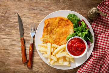 plate of fried breaded chicken meat or Schnitzel with french fries and salad