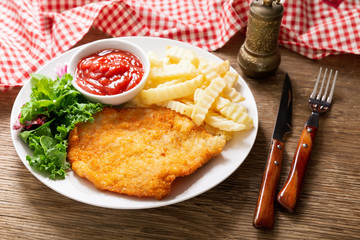plate of fried breaded chicken meat or Schnitzel with french fries and salad